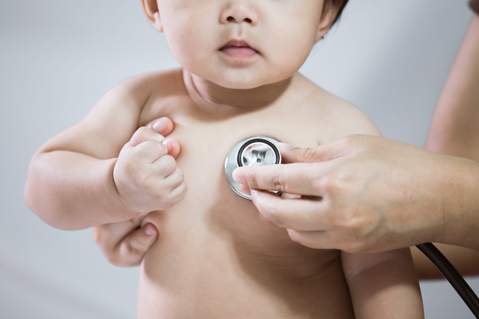 Doctor examining asian baby girl and listen her heart beat with